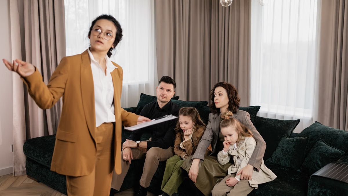 A real estate agent presenting property options to a family in a living room setting.